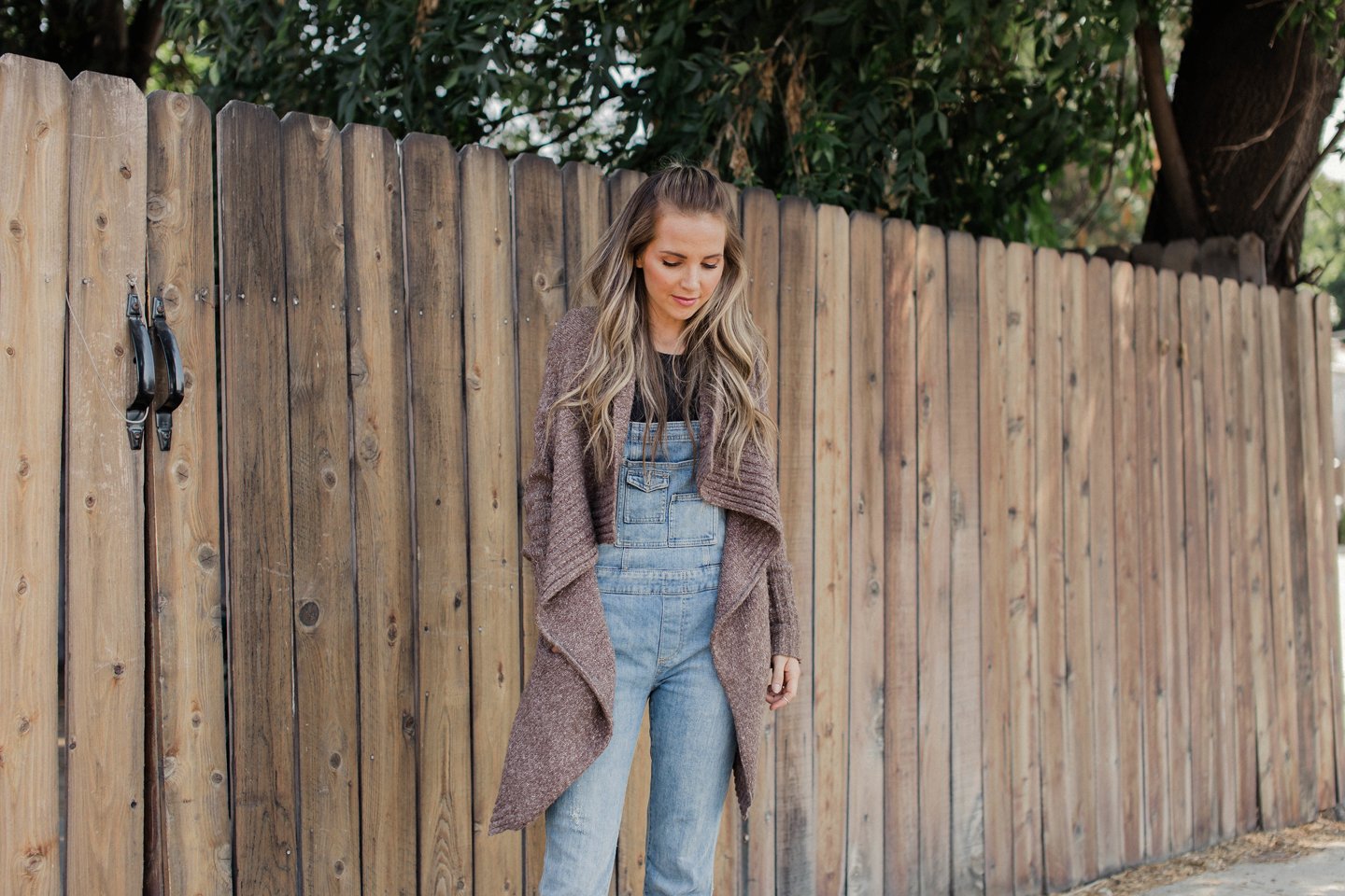 layer your overalls underneath an oversized cardigan sweater for a fall look