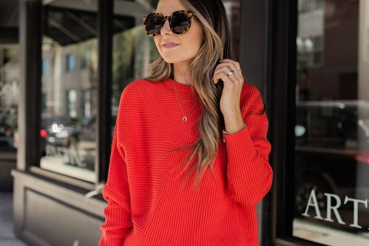 a chunky red sweater and tortoise shell frame glasses