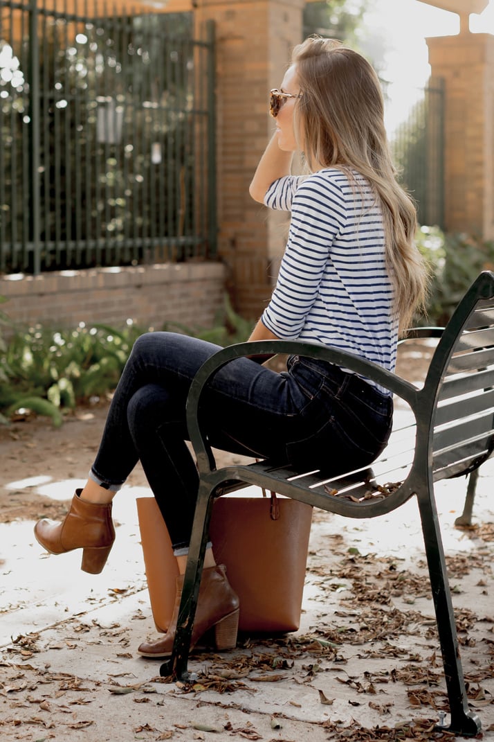 stripes, dark jeans, and cognac accessories