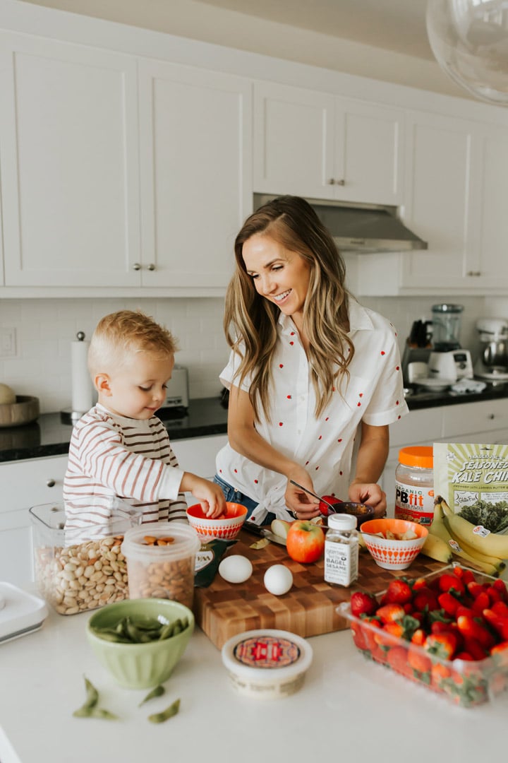 mom and son in the kitchen with healthy snacks on a cutting board