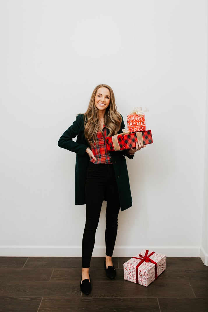 woman in green coat with stack of christmas presents