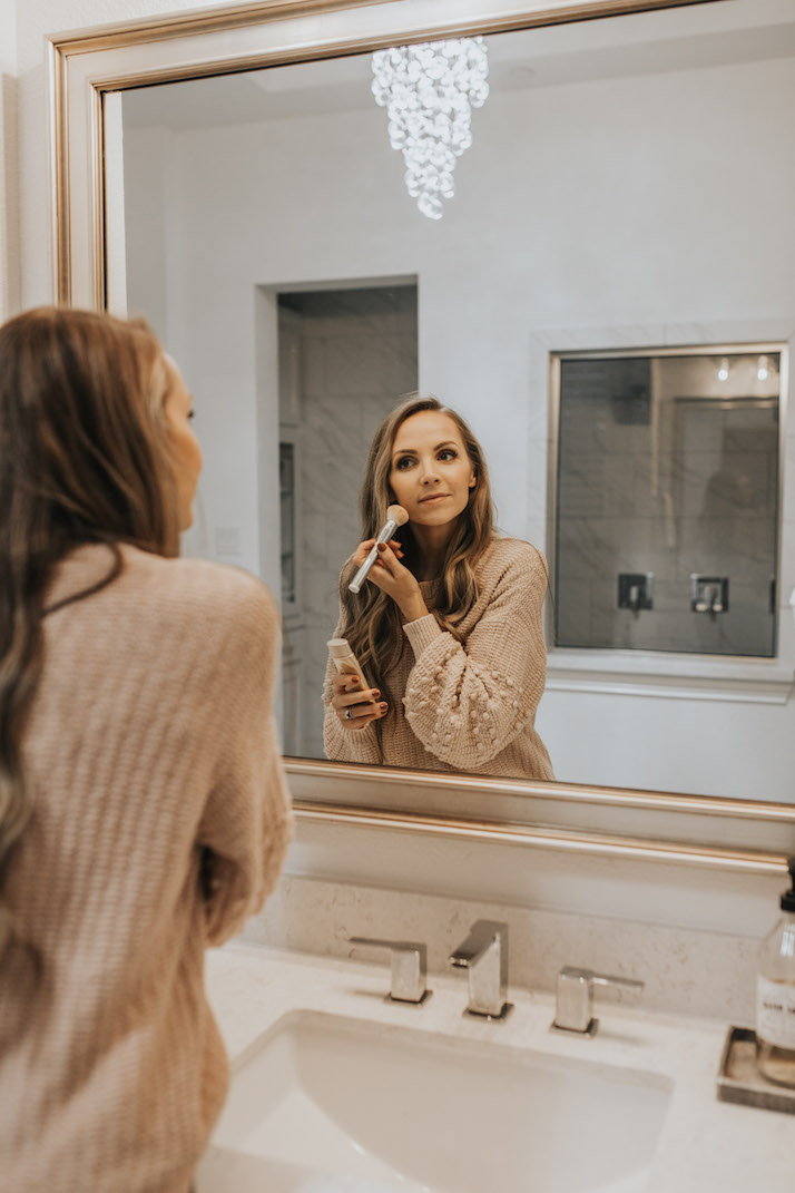 putting on makeup in a mirror with BB cream from Jane iredale