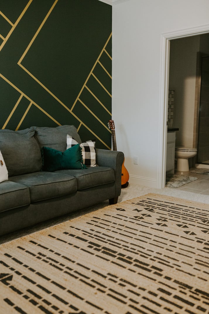 gold and green wall with blue gray couch and aztec rug