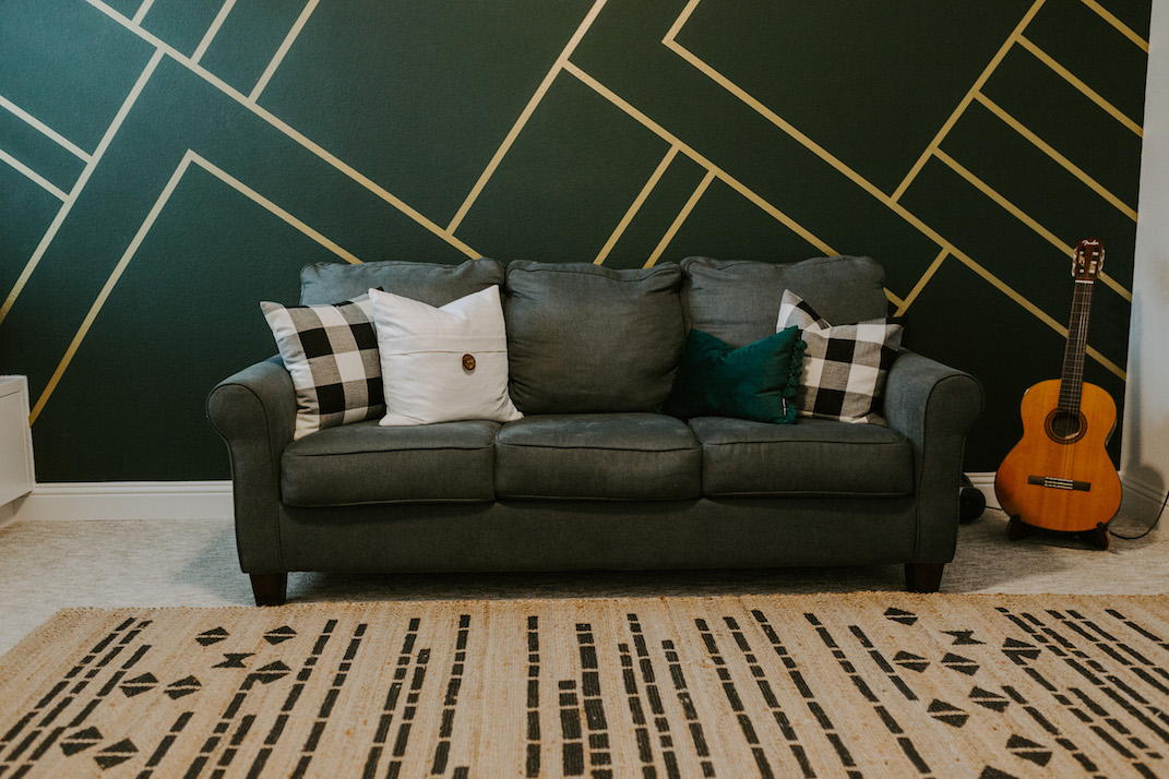 gold and green wall with blue gray couch and aztec rug
