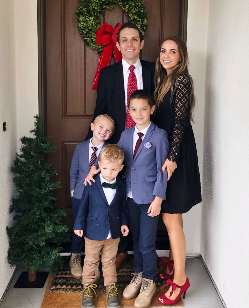 family in front of door with wreath and christmas tree