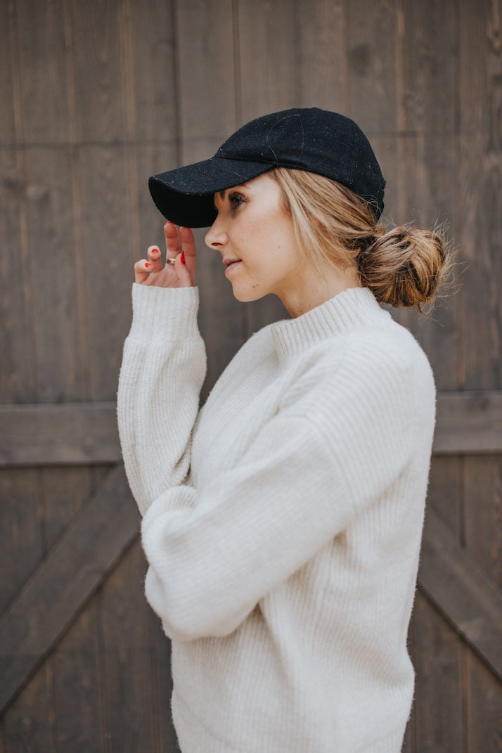cream sweater with black baseball cap