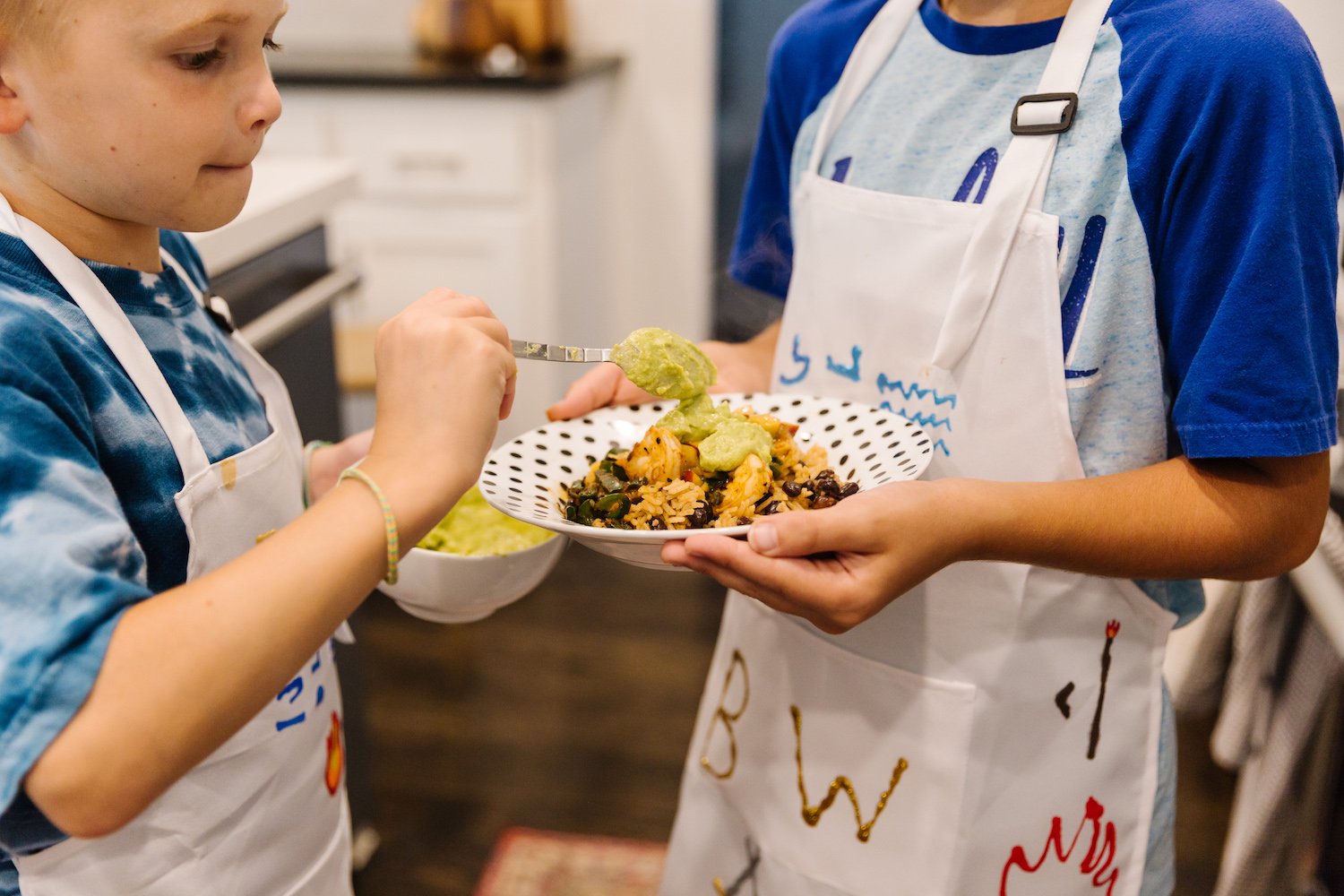 Cooking with kids - Fos plating his black bean and shrimp bowl with guacamole