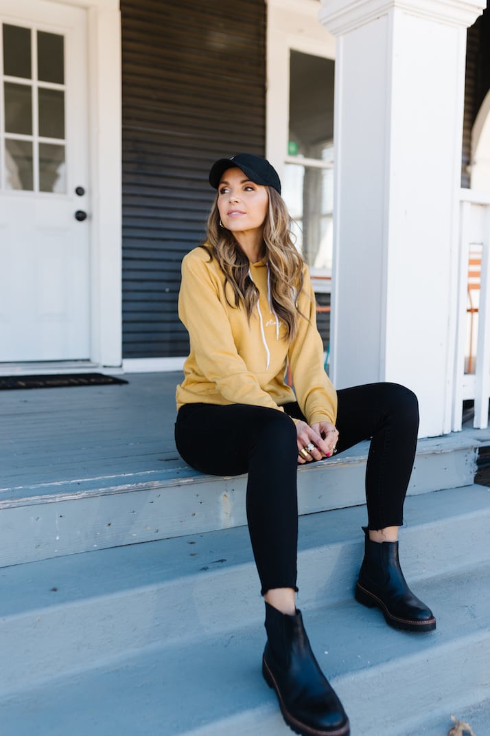 graphic sweatshirt with black boots and baseball cap