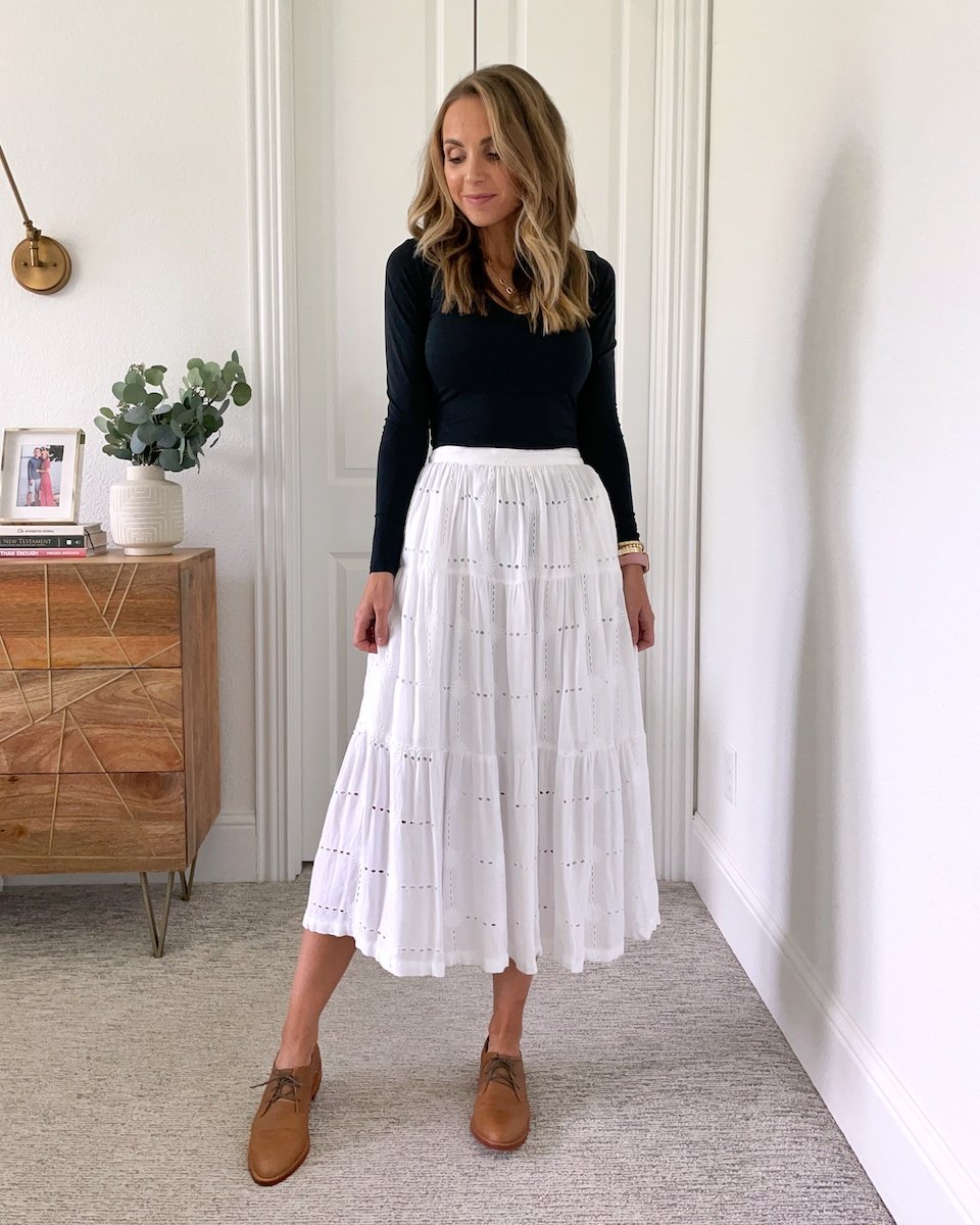 white skirt with black bodysuit and brown oxford shoes
